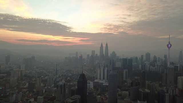 燃烧的天空映衬着吉隆坡摩天大楼与雾和薄雾的早晨。视频素材