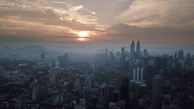 燃烧的天空映衬着吉隆坡摩天大楼与雾和薄雾的早晨。视频素材