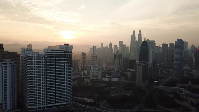 燃烧的天空映衬着吉隆坡摩天大楼与雾和薄雾的早晨。视频素材