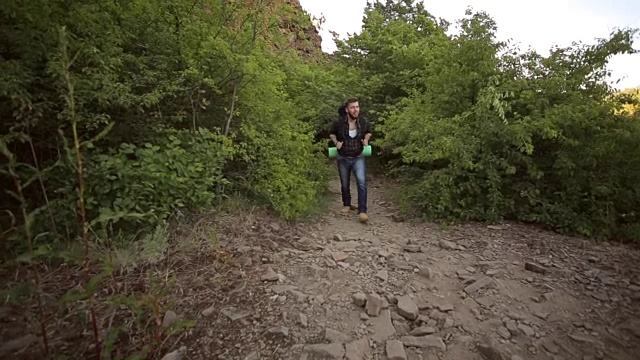 一个年轻人背着背包在山里旅行。视频素材