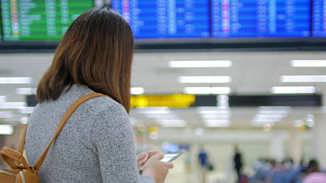 一名女乘客在离港机场办理登机手续前，用手机在数字登机牌上检查她的航班视频素材