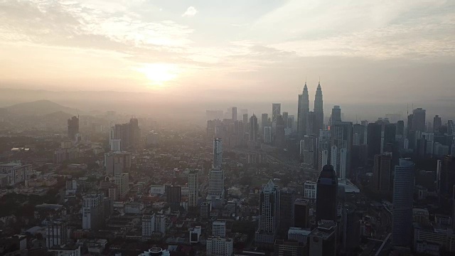 燃烧的天空映衬着吉隆坡摩天大楼与雾和薄雾的早晨。视频素材