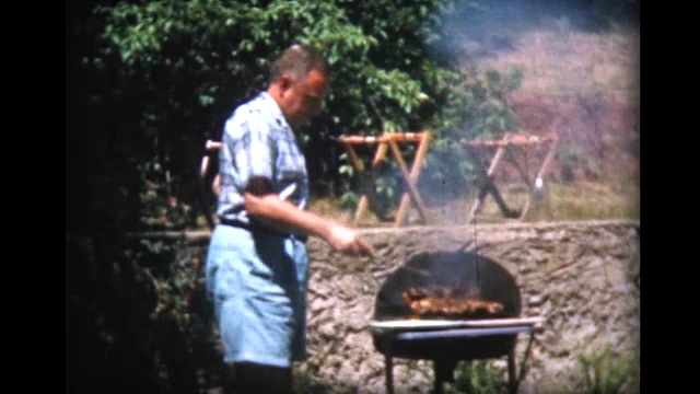 1957年，一名男子在露天烤架上烹饪和切肉视频素材