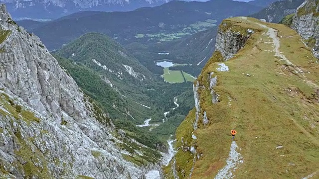 空中男子在高高的山脊上奔跑，俯瞰着下面美丽的山谷视频素材