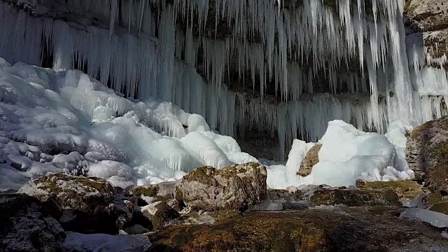 在阳光明媚的冬天，空中的山河在闪闪发光的大冰柱下流淌视频素材