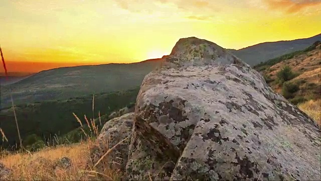 徒步者波夫缓慢地移动过山岩石向夕阳橙色的天空视频素材