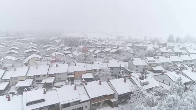 鸟瞰图:冬日里，在宁静的郊区城市里，飞翔在白雪覆盖的房屋上方视频素材