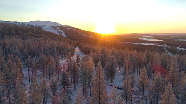 镜头:金色的冬日太阳在冰冻云杉森林和小滑雪场后面落下视频素材