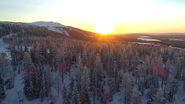 镜头:金色的冬日太阳在冰冻云杉森林和小滑雪场后面落下视频素材