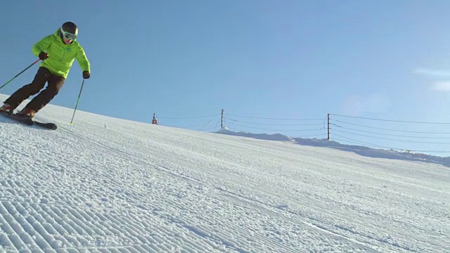 慢动作跟踪完美的雪道与滑雪者雕刻下斜坡视频素材