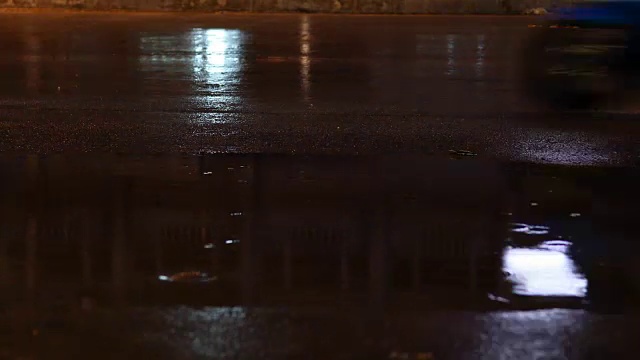 夜晚的街道在雨天的白天，雨水滴在水坑里，汽车行驶在柏油路上视频素材