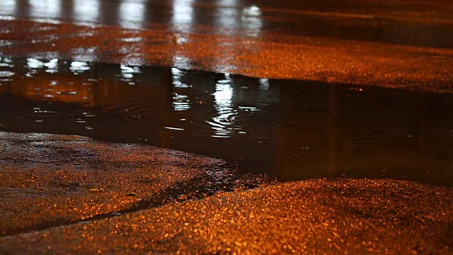 夜晚的街道在雨天的白天，雨水滴在水坑里，汽车行驶在柏油路上视频素材