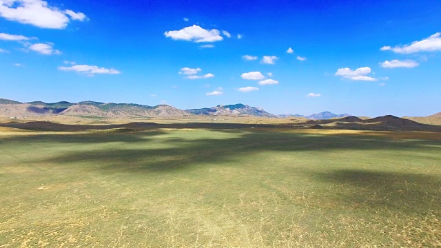 航拍:以蓝天为背景的草原和丘陵景观视频素材