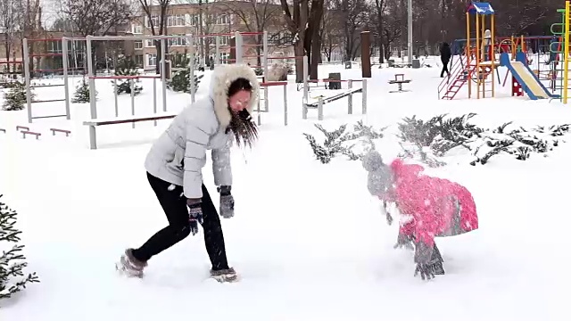 两个女孩，母亲和女儿，在冬天霜冻的一天在公园扔雪。视频素材