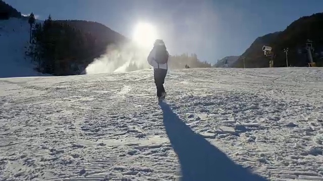 女旅行者在冬季登山，徒步在冬天寒冷的雪天，女孩剪影在自然的蓝天与明亮的日落和美丽的风景，自由的概念视频素材