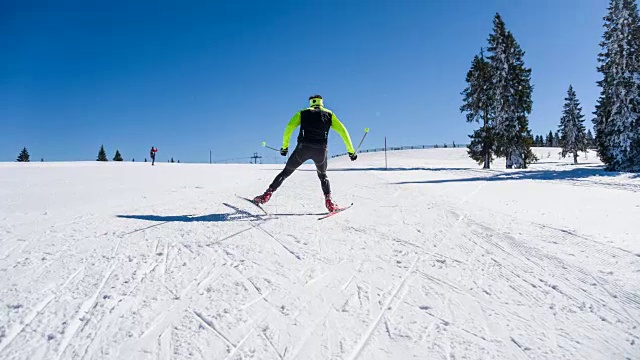 越野滑雪者在一个阳光明媚的冬日滑着雪上山视频素材