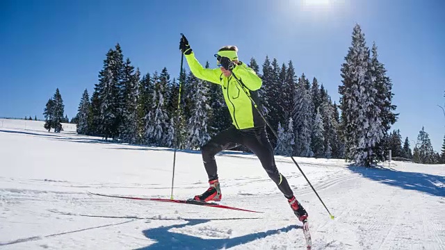 在一个阳光明媚的冬日里，越野滑雪者全功率滑冰上山滑雪视频素材