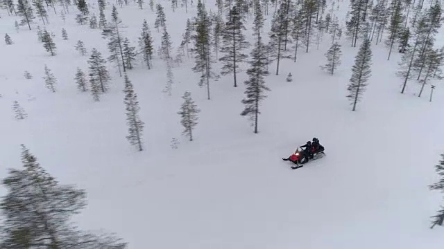 特写:在挪威森林覆盖的山坡上，男人和女人骑着雪地摩托视频素材