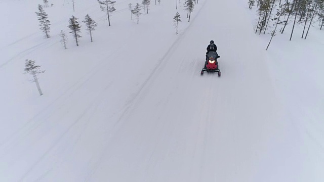 空中拍摄，特写:一对夫妇在冬天的雪地上骑着雪地车视频素材