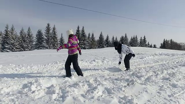 母亲和女儿有乐趣在冬天扔雪球和微笑视频素材