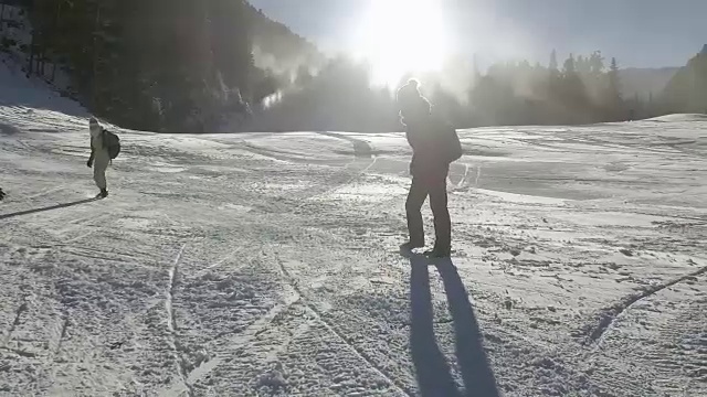 在冬日里，一个孩子兴奋地从山上滑下来，背景是太阳，慢镜头视频素材