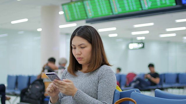 一名女乘客在离港机场办理登机手续前，用手机在数字登机牌上检查她的航班视频素材