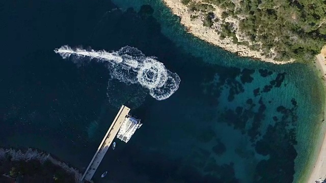 高空高空拍摄的极端摩托艇驾驶在一个小海湾与绿色海水的圆圈。停泊在码头附近的帆船和小船。视频素材