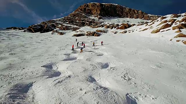 在阿尔卑斯山的一个斜坡上飞过一群滑雪者视频素材