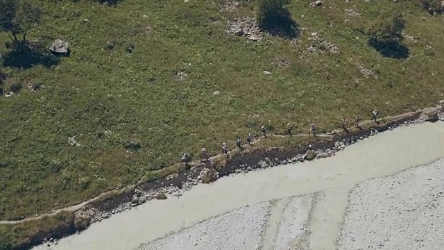 无人机观徒步旅行组沿山河行走。山之旅视频素材