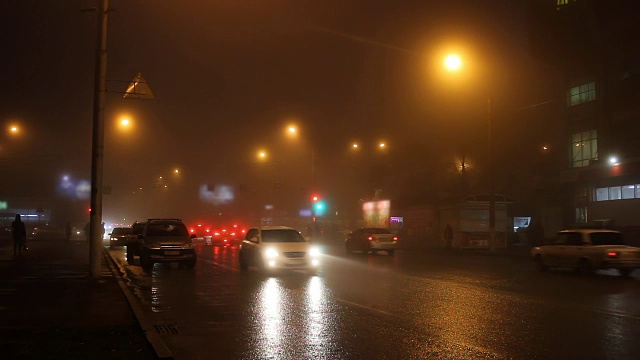 夜晚城市的街道上有雾，路上有汽车。视频下载