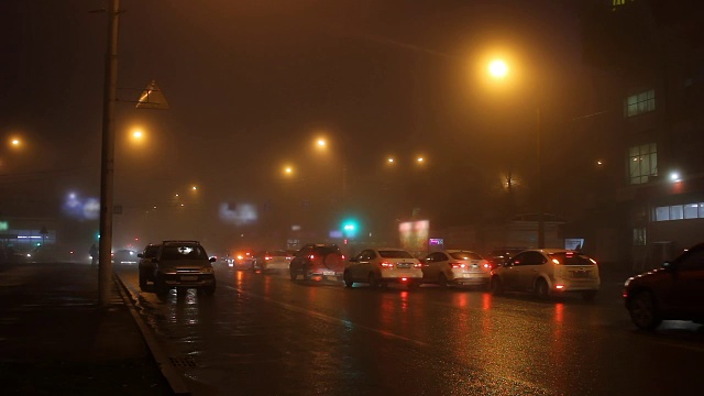 夜晚的灯光在雾中的城市和道路上的汽车。视频下载