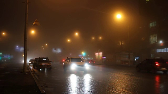 夜晚的灯光在雾中的城市和道路上的汽车。视频素材