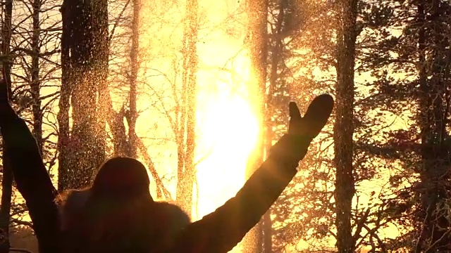 慢镜头:顽皮的女孩在金色的夕阳下向空中抛雪花视频素材