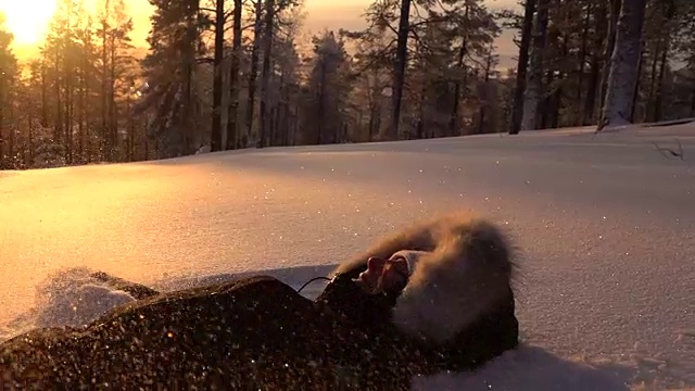 慢镜头:在金色的夕阳下，快乐的女孩躺在山顶的雪地上视频素材