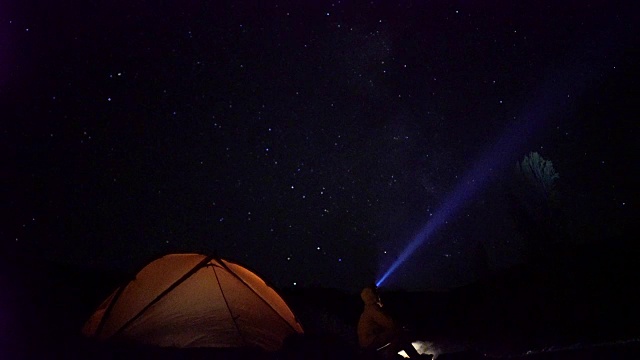 夜晚在露营上空移动的星星。男人喜欢篝火。视频素材