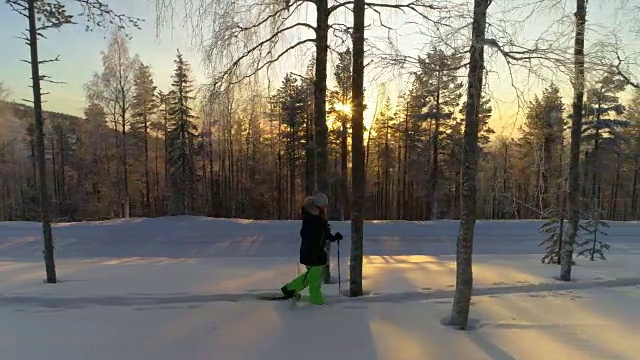 在金色的冬日夕阳下，穿着冬衣的女孩踏在厚厚的雪地上视频素材