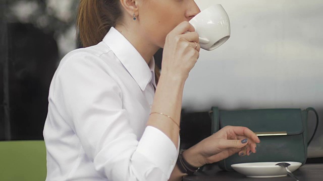 年轻漂亮的女人在街头咖啡馆拿着杯子视频素材