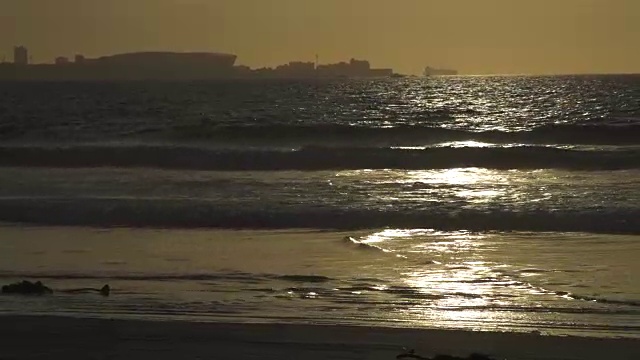 海浪拍打着金色的海岸/背景中的体育场/开普敦/南非视频下载