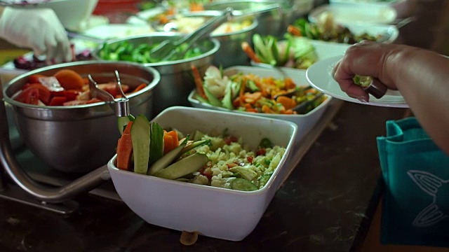 特写女人把食物放在她的盘子里从自助餐。视频素材