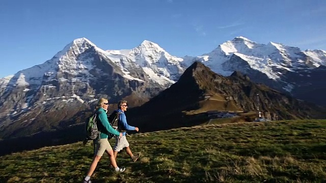 徒步旅行的夫妇穿过山下的草地视频素材