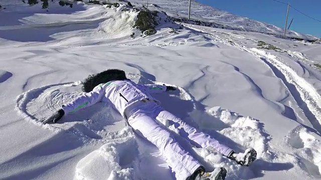 年轻女子摔倒了，做了个雪天使。超高清4K摄像机库存镜头视频素材