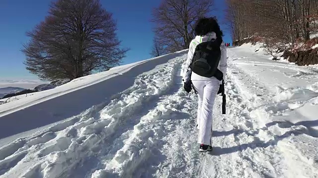 失落活跃的女人背着背包走在雪地上。超高清4K摄像机库存镜头视频素材