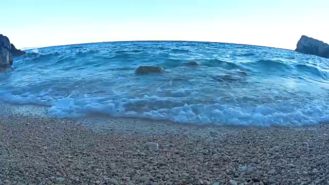 海洋沙滩。日落时海浪拍打着卵石海岸。视频素材