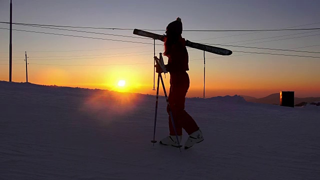 在夕阳的照耀下，滑雪者爬到山顶开始滑雪。视频素材