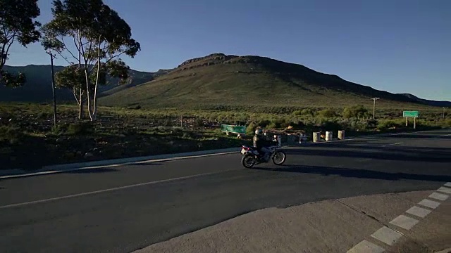 镜头光晕和平移拍摄的摩托车在道路/西开普敦/南非视频素材