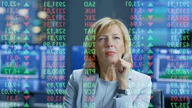 股票市场女性高级经理看着预测的股票号码和图表。在她满是屏幕和数据的房间后面。视频素材