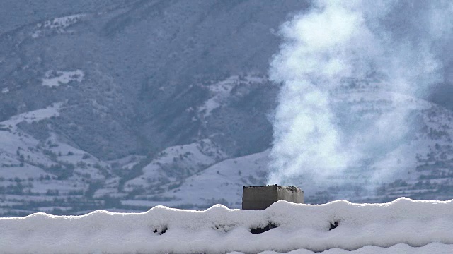 白雪覆盖的屋顶和烟囱冒出的烟，4k背景概念视频素材