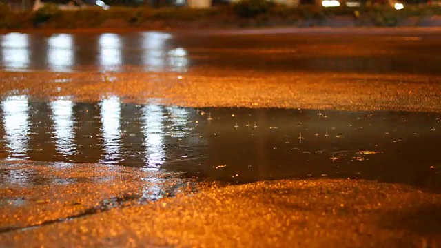 夜晚的街道在雨天的白天，雨水滴在水坑里，汽车行驶在柏油路上视频素材