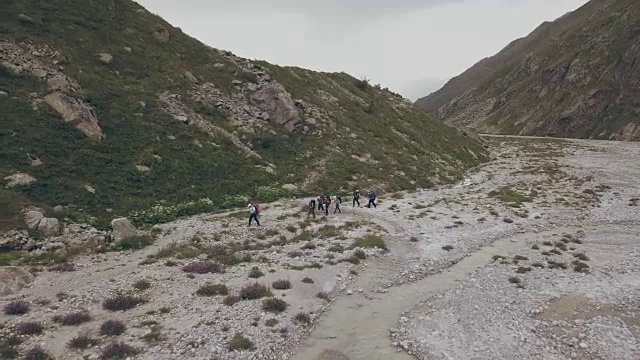 鸟瞰旅游团行走在山间小径上的背景山峰视频素材