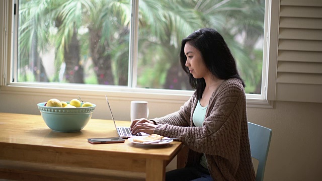 年轻女子在家里用笔记本电脑工作视频素材